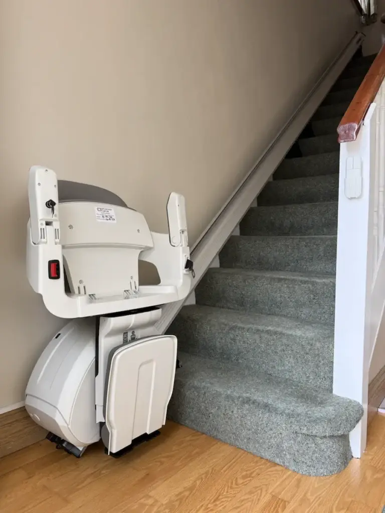 HomeGlide folded at the bottom of a carpeted straight staircase, fitted by O’Connor Carroll